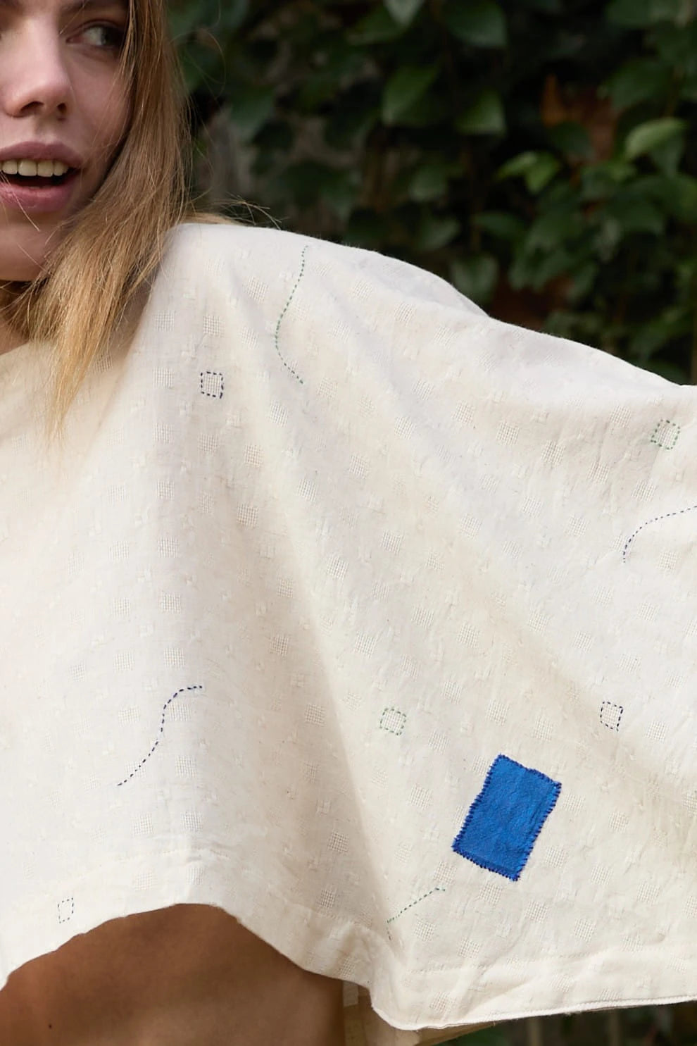 White Canvas Blue Owl Top in blue handwoven dobby cotton (100%) with applique work and Kantha stitching, angled view on model